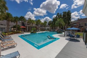 Pool area with sun chairs and patio tables with umbrellas